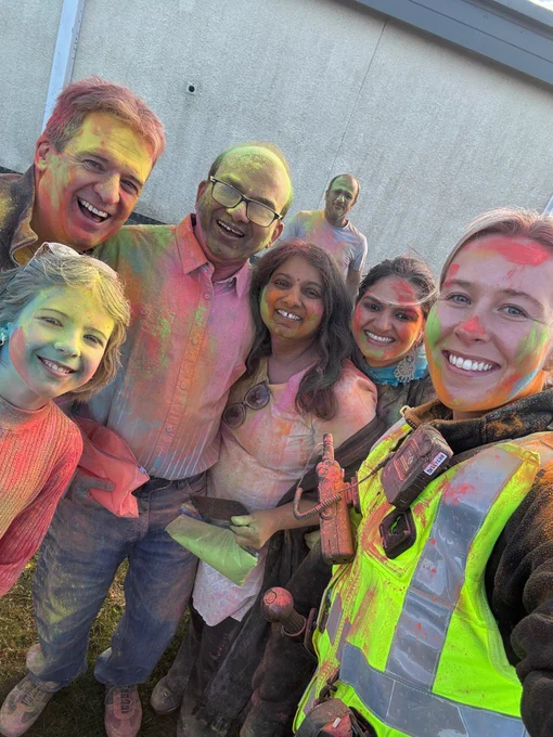 Female police officer with members of the public covered in colourful powder.