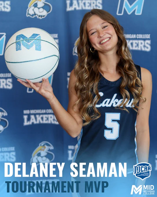 Delaney Seaman from the Women's Laker Basketball Team poses with a Mid Michigan College themed basketball in front of a backdrop.

