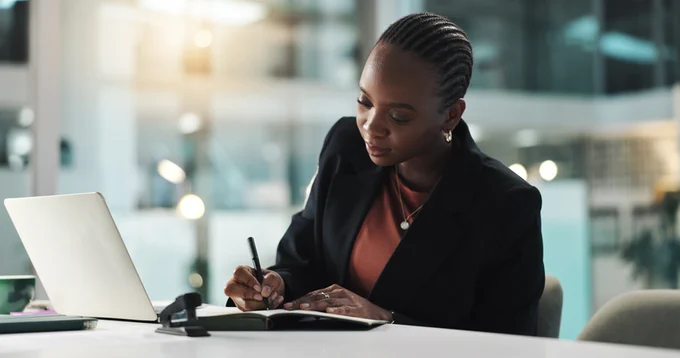 Woman in an office setting writing in a notebook 