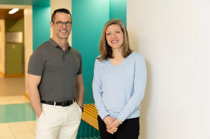 Bob Kiser and Leah Burt photographed in front of a wall.