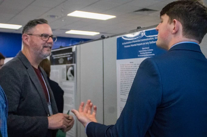 Male HDFS faculty member, Ray Petren, talks to male student at Undergraduate Research Fair. 