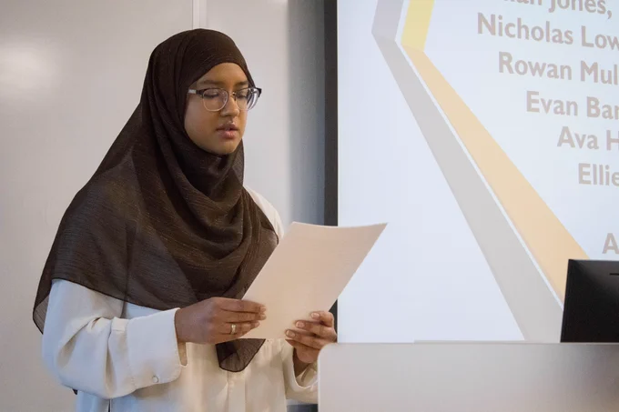 Female student reads an excerpt from a paper at Undergraduate Research Fair. 