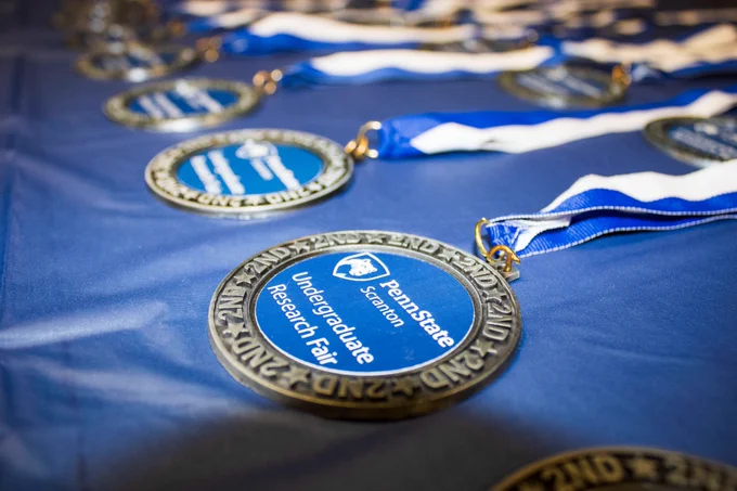 Blue and white medals that read 'Penn State Scranton Undergraduate Research Fair.'