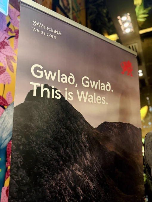 A banner with a picture of a mountain, and text reading Gwlad, Gwlad. This is Wales.