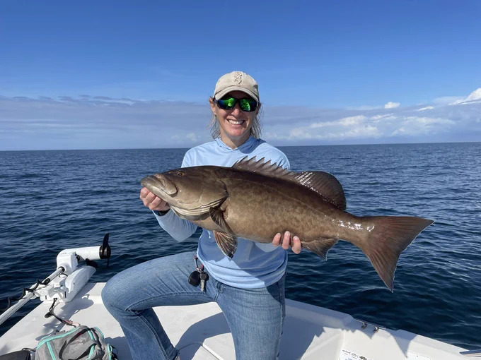 An angler proudly displaying their saltwater catch on a vessel with an open Florida waterway in the background.