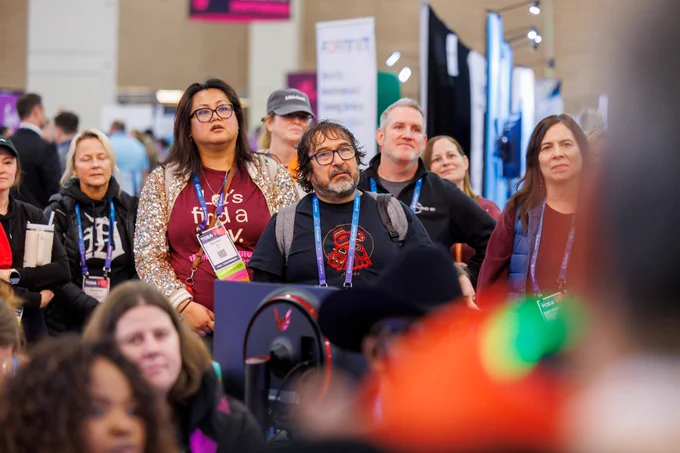 A photo of a group of people watching and listening to a demonstration.