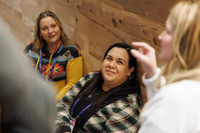 A photo of a woman smiling up at someone who is talking. 