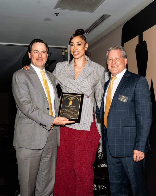 Dearica Hamby posing for a photo with her Hall of Fame plaque and Wake Forest members.