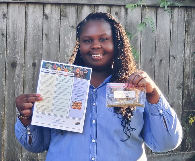 a woman smiling holding spice packet and a fact sheet