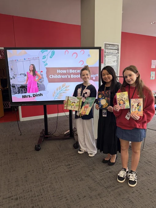 Students standing with Mrs. Dinh holding her published books. 