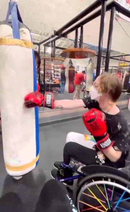 Wheelchair user punching a punching bag. 