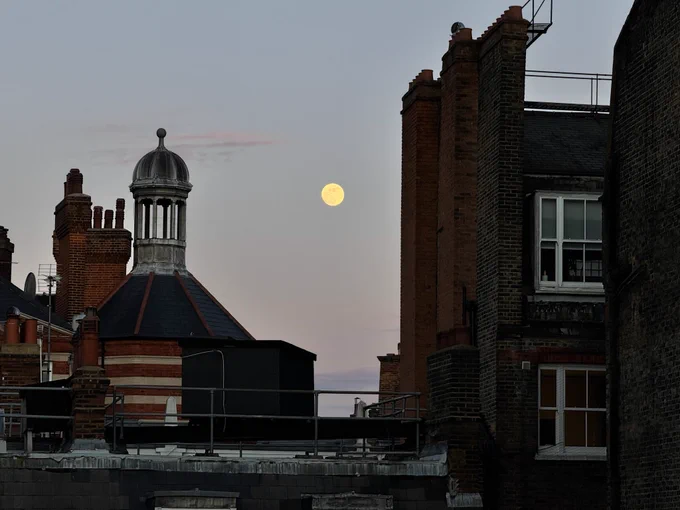 Full moon at twilight over some Edwardian buildings.