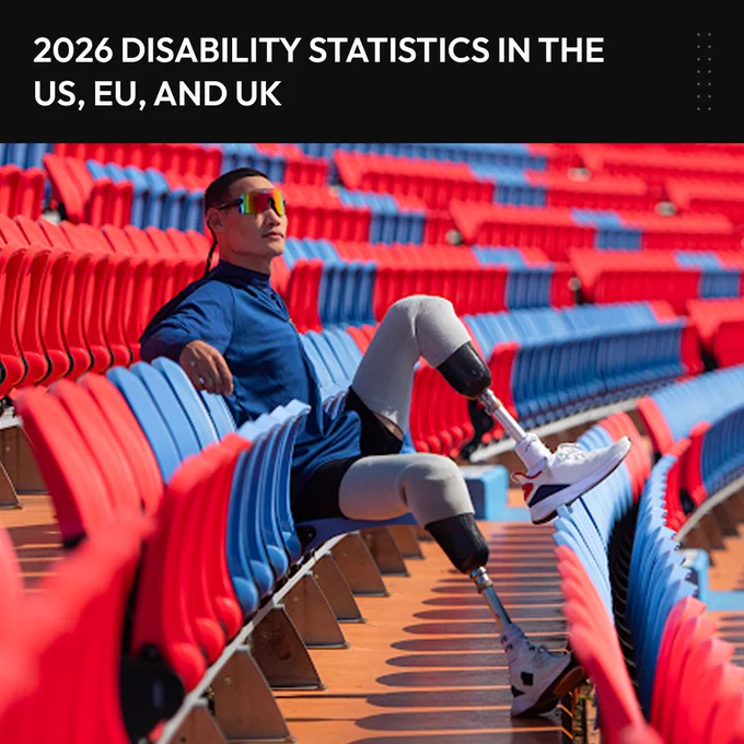 Man with prosthetic legs wearing running shoes and athletic wear sits in the bleachers of a stadium. 