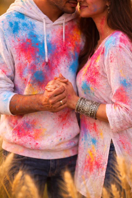  Detailed Prompt:
High-resolution photorealistic waist-up vertical portrait of a South Asian couple standing closely in a wheat field during golden hour. The man wears a white hoodie and the woman wears a white kurta, both heavily splattered with cyan, magenta, and yellow Holi powder. The woman's ornate silver cuff bracelet and the man's silver ring are in sharp focus as they hold hands gently. Heads slightly cropped. 85mm lens, f/1.8, shallow depth of field, creamy bokeh, warm cinematic sunlight, vibrant cultural celebration aesthetic.
Negative Prompt:
text, watermark, logo, distorted hands, extra fingers, low resolution, cartoon, illustration, dark shadows.