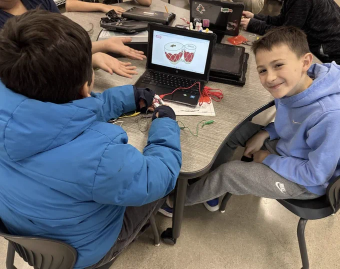 Two students work with their Makey Makey, exploring various items to attach to make drum sounds. 