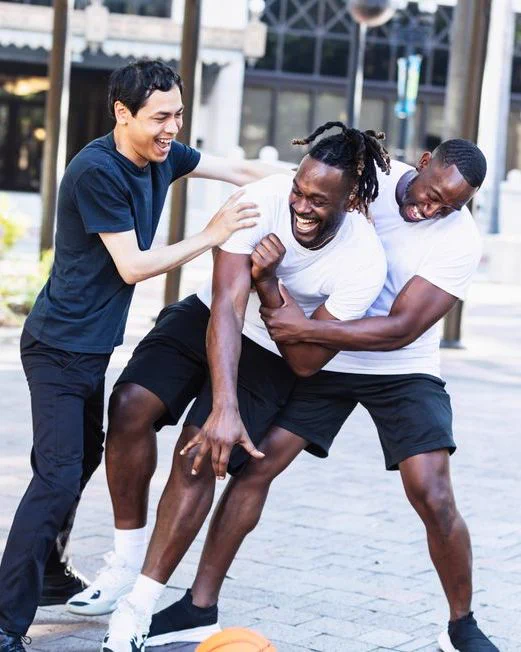 Group of men laughing and playing basketball. 
