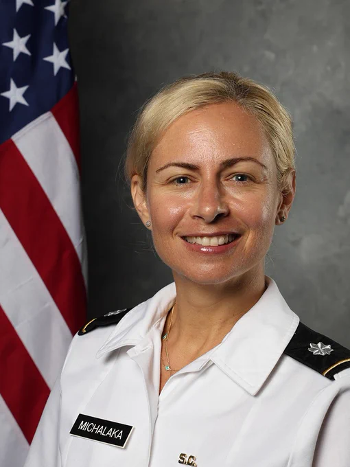 Dimitra Michalaka, smiling in a white uniform from The Citadel. The American flag is to her left.