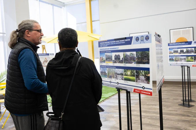 Two people looking at an informational board about the Central Avenue Blue/Silver Line Plan.