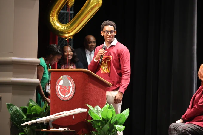 Parker standing on stage with microphone giving recognition to those who helped him