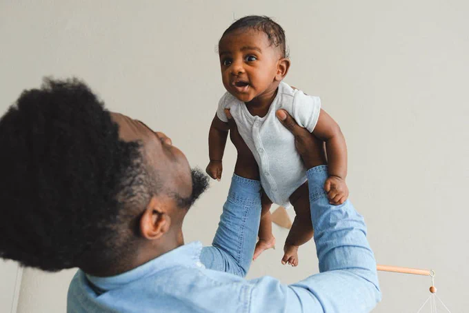 A loving father joyfully lifts his baby in an intimate family moment, expressing warmth and connection.