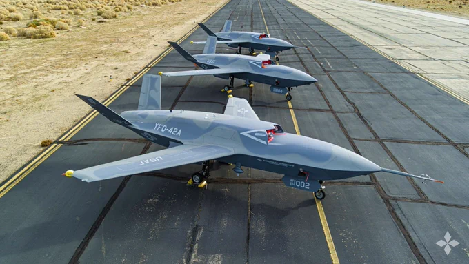 Three General Atomics Aeronautical Systems YFQ-42Agray uncrewed combat jets lined up on a runway in a desert environment, each marked with US Air Force insignia and model numbers.
