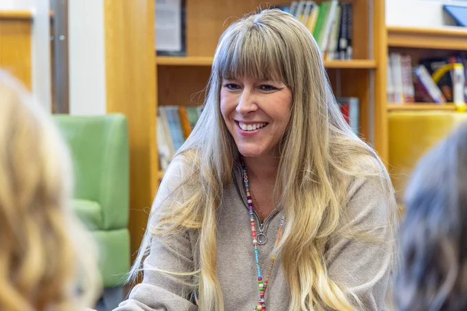 Lacey Lee, Lakewood Elementary school social worker, smiling in a library with two students.
