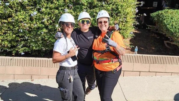 Three Sonic Fiber field service team members with arms around each other, smiling and throwing up peace signs to all of our awesome members