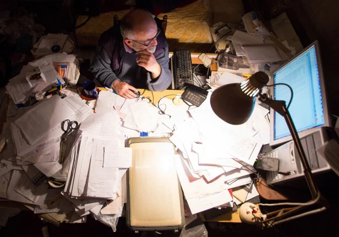 A businessman surrounded by paperwork. He needs a bespoke business system from Decent Group.