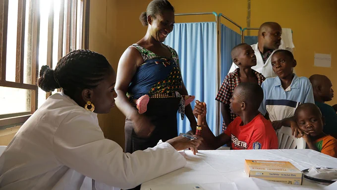 Healthcare worker attending to a mother and her children during a community medical outreach program in Otakikpo, Rivers State.