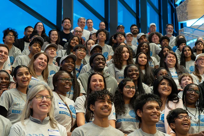 A large group of smiling people sit together in stands.