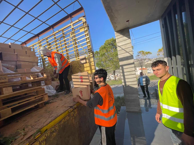 People in high vis vests unloading supplies from a van. 