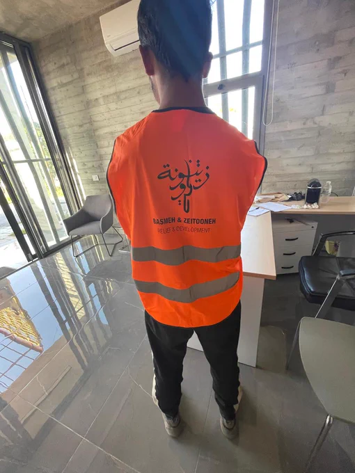 A view of the back of a staff member wearing a high vis vest. 