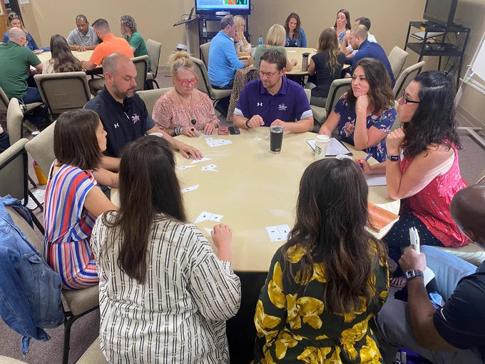 Teachers circled around a table at an Experiential Site Visit.