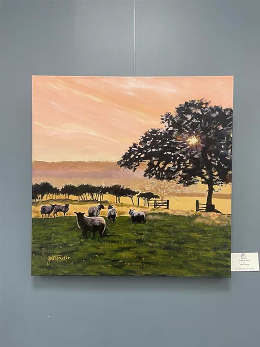 A painting depicts a serene pastoral scene with sheep grazing on green grass. A large tree is silhouetted against a warm sunset, and a fence stretches across the landscape. The sky is a gradient of pink and orange hues.