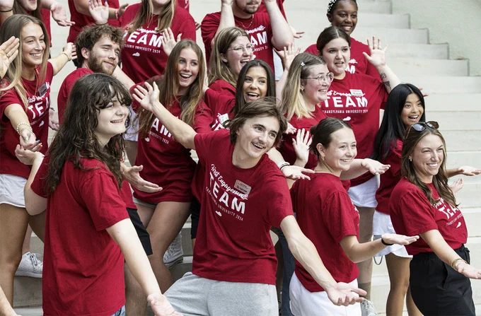 students posing in front of a campus building
