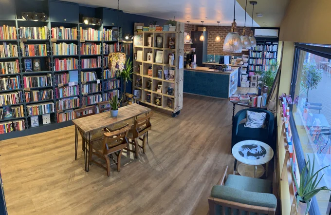 Interior of a bookshop with shelves and cosy seating and tables.