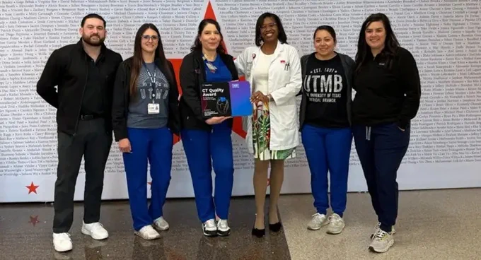 Six employees stand together with two women in the middle hold an award