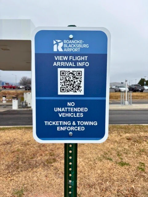 Sign - ROA logo. View flight arrival info with QR code. No unattended vehicles. Ticketing and towing enforced