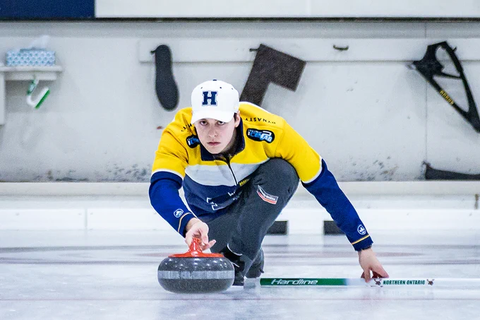 A person wearing Humber Hawks apparel is curling.
