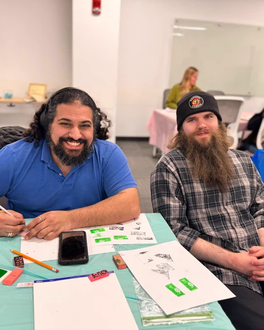 UB student (left) carves a stamp with event organizer Logan Walters