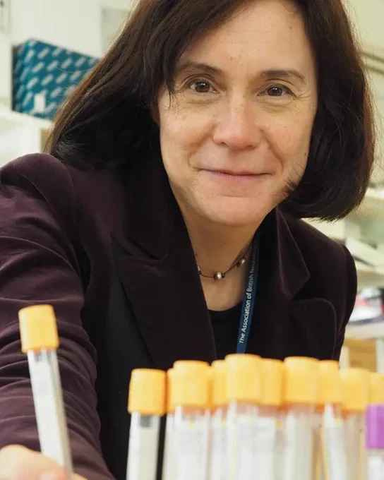 Female wearing a brown top in a research lab, holding sample tubes.