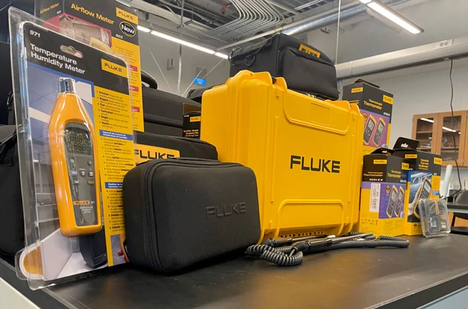 black and yellow Fluke lab equipment sit on a table in a lab setting