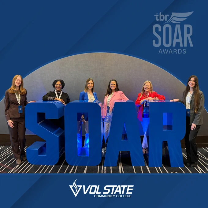 Vol State students and college representatives stand in front of a sign of letter spelling out SOAR. 
