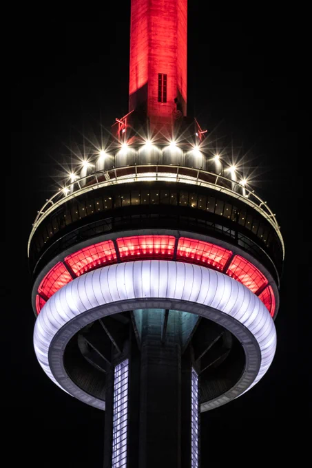 Closeup of the CN Tower at night lit in red and white / Gros plan de la Tour CN la nuit, illuminee en rouge et blanc
