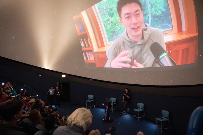Event photo from AIMLX26. Image depicts a Zoom call with an expert on the planetarium screen. 