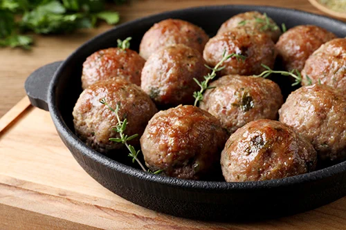 Black skillet with browned meatballs