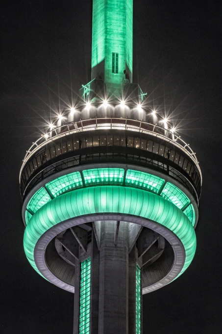 Closeup of the CN Tower at night lit green / Gros plan de la Tour CN illuminée en vert la nuit