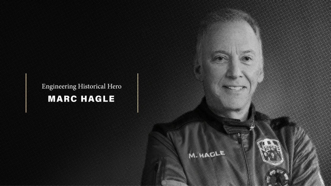 A black-and-white halftone portrait of Marc Hagle smiling, wearing a jacket with "M. Hagle" on the chest. Text on the left reads "Engineering Historical Hero" above his name in bold white letters, with gold vertical lines and a gold hexagon outline as decorative elements on a dark background.