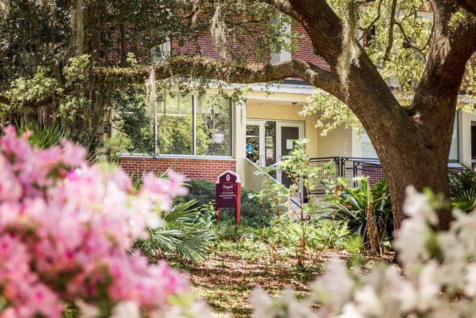The entrance and sign to Thagard Hall with pink and white flowers blurring the foreground