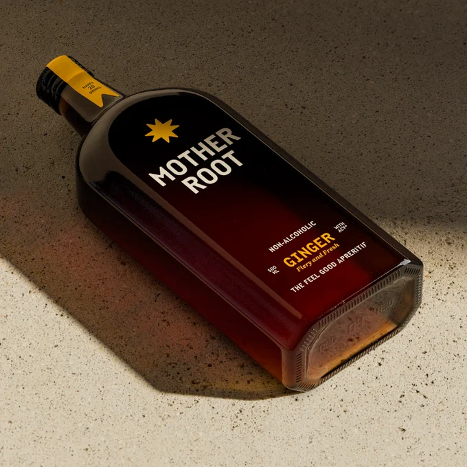 A sleek bottle of non-alcoholic ginger aperitif labeled "Mother Root" with a dark background and light highlighting its design.